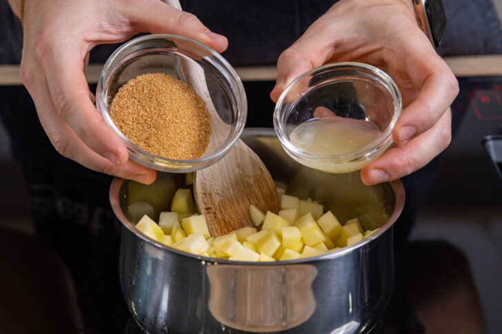 Zitronensaft und Zucker zu Äpfeln geben