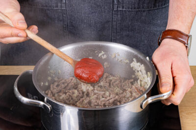 Tomatenmark zum Fleisch geben