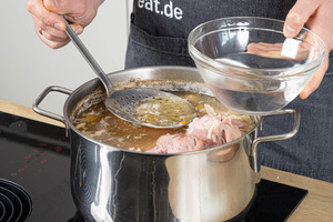 geronnenes Eiweiß vom Sud schöpfen