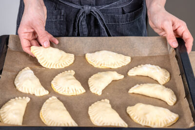 Hefeteig-Apfeltaschen mit Abstand auf dem Backblech verteilen