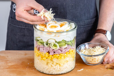 Käse über Schichtsalat nach Landfrauen-Art geben