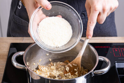 Parmesan unter das Steinpilzrisotto rühren