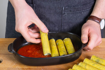 gefüllte Cannelloni in die Soße legen