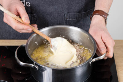 Sahne und Schmelzkäse zum Hackfleisch geben