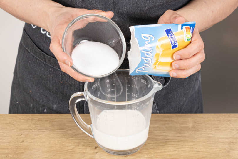 Zucker und Puddingpulver in Milch einrühren