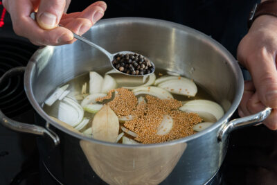 Pfefferkörner in den Topf geben