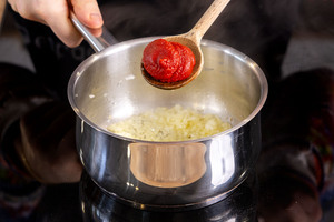 Tomatenmark zu den Zwiebelwürfeln geben