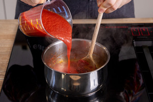 passierte Tomaten zu den Zwiebeln gießen