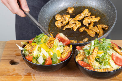 Hähnchenstreifen auf dem Salat portionieren