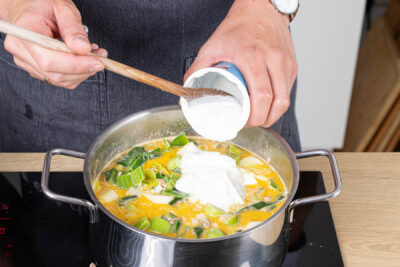 Saure Sahne unter die Lauchsupppe mit Hackfleisch rühren