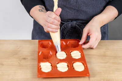 Teig in die Backform für Madeleines spritzen
