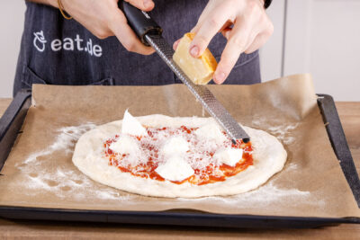 Parmesan über die Pizza reiben