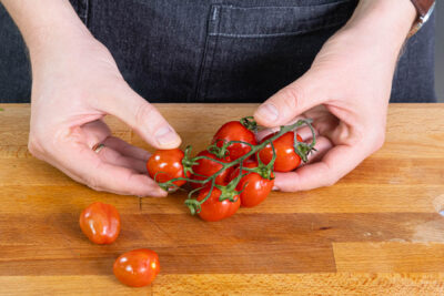 Kirschtomaten vom Strunk lösen und mit zum Ofengemüse mit Hähnchen geben