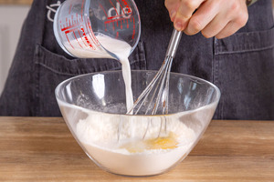 Milch in den Pfannkuchenteig gießen