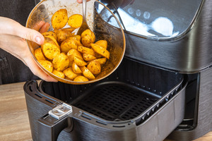 Rohe Kartoffeln in den Frittierkorb der Heißluftfritteuse geben