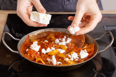 Feta zu der Tomaten-Paprika-Soße geben