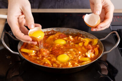 Eier in die Shakshuka schlagen