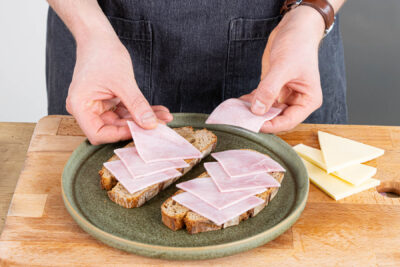 Schinken und Käse auf das gebutterte Brot legen