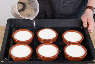 Milchreis in Förmchen füllen und Backblech in mit Wasser füllen