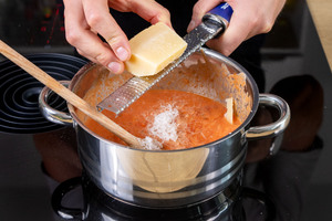 Parmesan in die Tomaten-Sahne-Sauce reiben