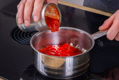Gehackte Tomaten in den Topf geben