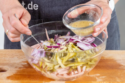 Dressing über den Wurstsalat geben