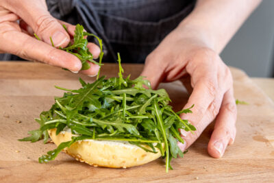 Rucola auf den Bagel geben