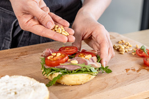 Pinienkerne auf dem Bagel verteilen