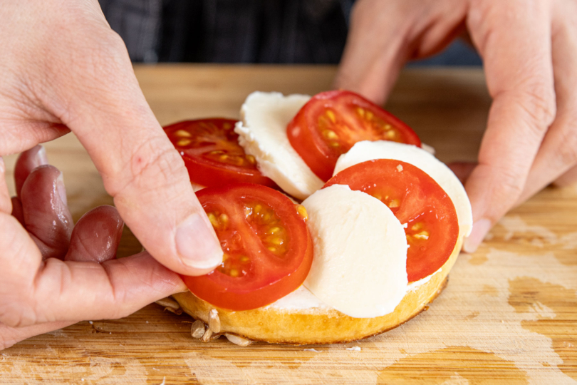 Bagel mit Tomaten- und Mozzarellascheiben belegen