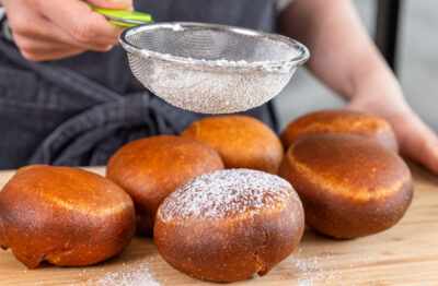 Berliner/ Krapfen mit Puderzucker bestäuben