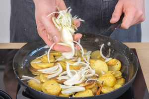 Zwiebeln zu den Bratkartoffeln geben