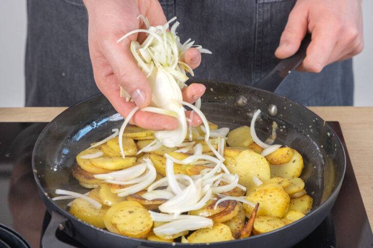 Zwiebeln zu den Bratkartoffeln geben