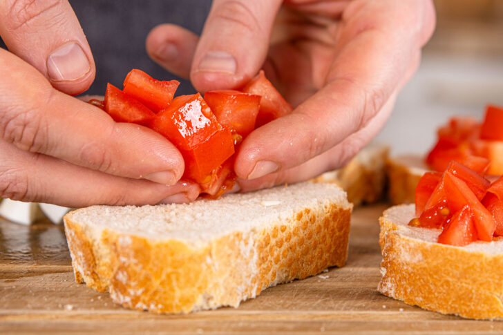 Tomaten auf das Baguette geben