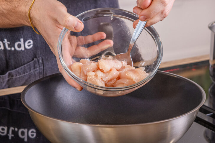 Hähnchen in den Wok geben