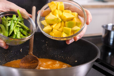 Zuckerschoten und Mango in den Wok geben
