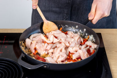 Hähnchen zum Gemüse in die Pfanne geben