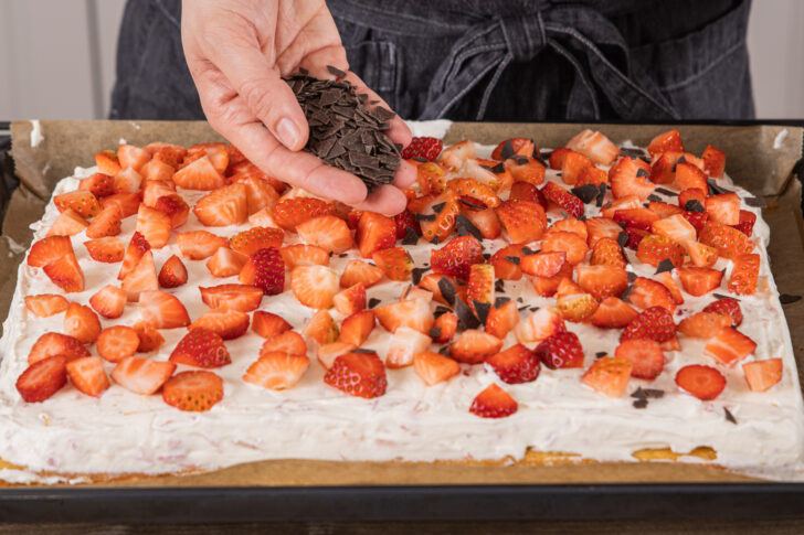 Schokoraspel auf den Fantakuchen mit Erdbeeren verteilen
