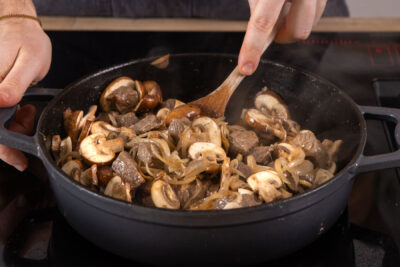 Pilze und Zwiebeln mit dem Gulasch anbraten