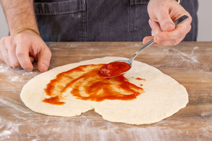 Herzpizza mit passierten Tomaten bestreichen