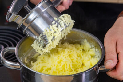 Kartoffeln durch Kartoffelpresse geben