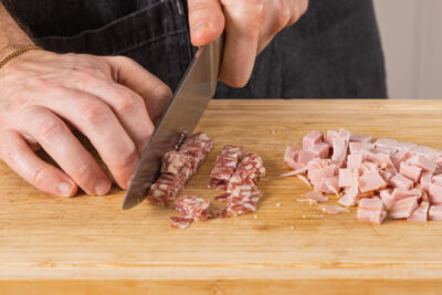 Salami und Schinken in Würfel schneiden