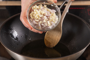 Knoblauch und Zwiebeln in die Pfanne geben