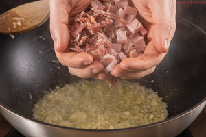 Salami und Schinken in die Pfanne geben