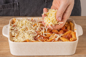 Den Nudelauflauf mit Reibekäse bestreuen