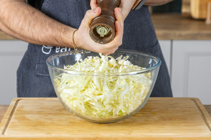 Spitzkohlsalat mit Pfeffer würzen