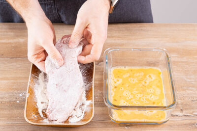 Schnitzel in Mehl und verquirltem Ei wenden
