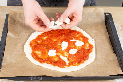 Mozzarella auf die Pizza zupfen