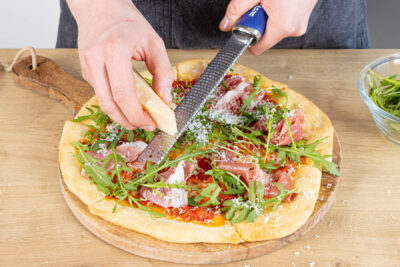 Pizza Parma mit Rucola, Parmaschinken und Parmesan belegen