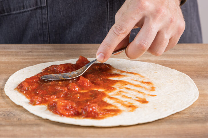 gehackte Tomaten auf der Tortilla verteilen