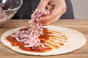 Schinken und rote Zwiebeln auf der Tortillas verteilen